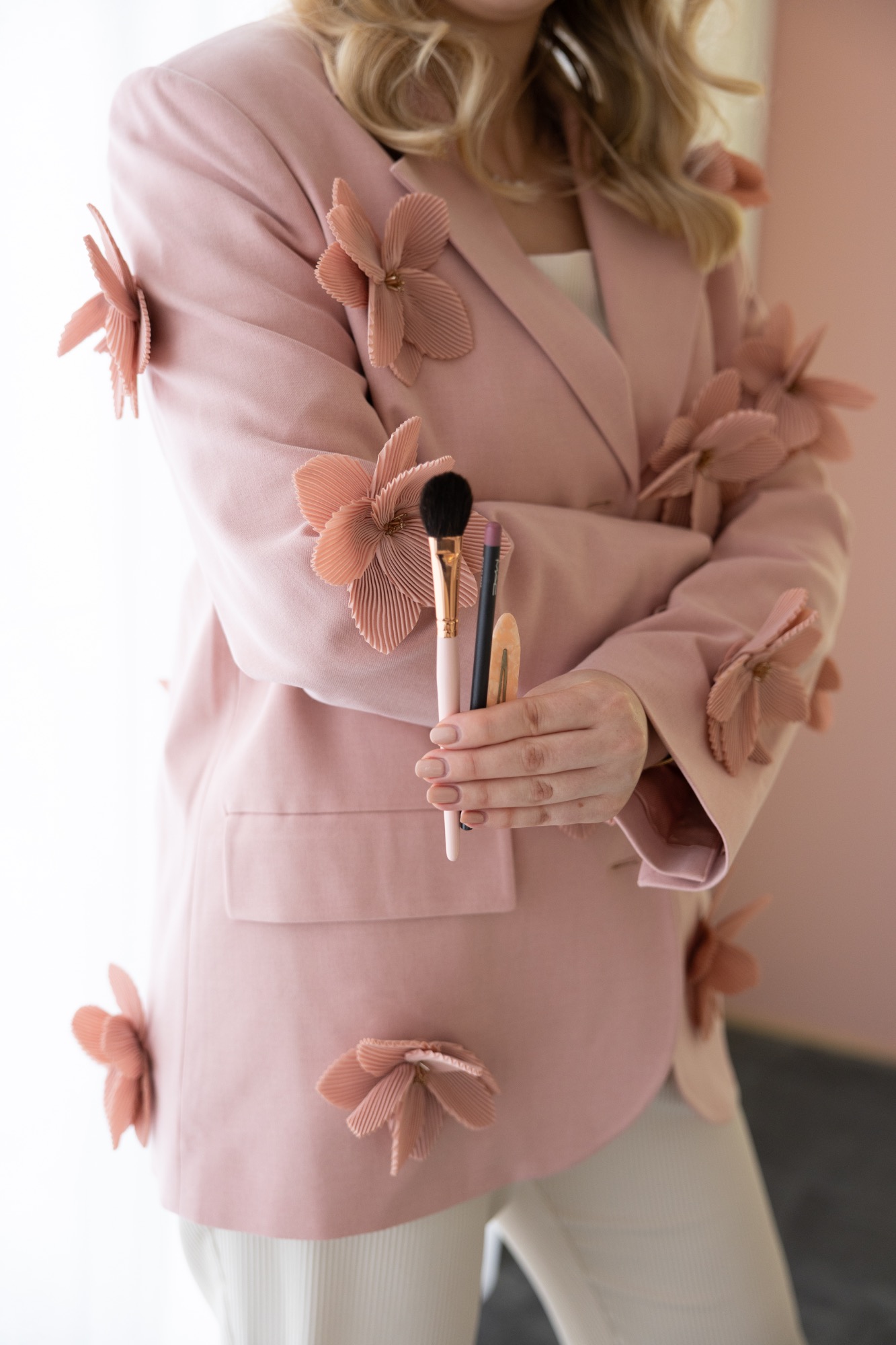 Sabine mit roséfarbenem Blazer und Make-up-Pinseln